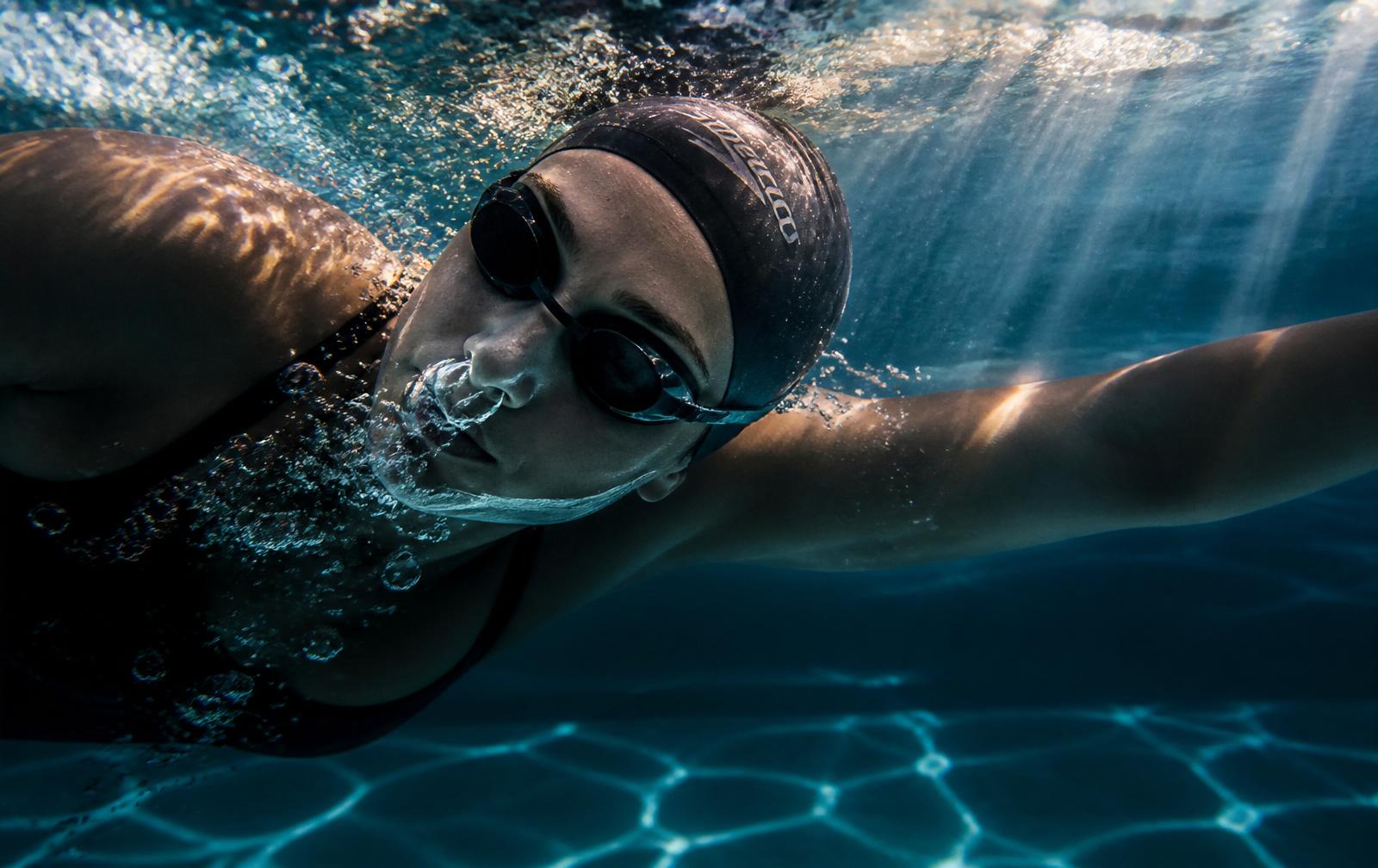 Underwater freestyle swimmer exhaling a smooth stream of bubbles